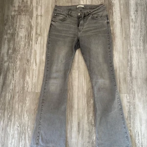 Grå bootcut jeans  - Säljer ett par grå bootcut jeans klassiska fickor och knappgylf. Jeansen har en snygg, lite utsvängd passform. Perfekta för dig som gillar en avslappnad och trendig look. Dom har en liten ”fläck” på ena benet då jag spillde lite lim, men inte så märkvärdigt när man har på sig dom😍