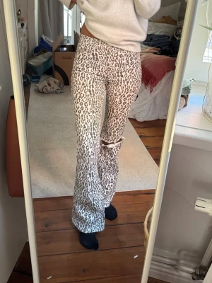 Leopardmönstrade utsvängda jeans - Säljer ett par snygga leopardmönstrade jeans med utsvängda ben och hål på ena knät. Jeansen medelhög midja och är i stretchigt material som sitter tajt upptill. 💟