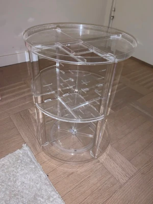 Roterande sminkorganiserare i akryl - Som ny. Snygg och praktisk roterande sminkorganiserare i transparent akryl. Perfekt för att förvara borstar, läppstift och andra skönhetsprodukter. Flera hyllplan och fack gör det enkelt att hålla ordning på dina favoriter.