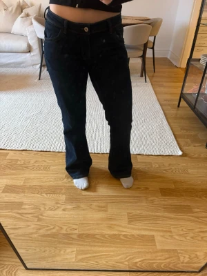 Mörkblå bootcut jeans med kontrastsömmar från H&M - Säljer ett par mörkblå bootcut jeans med snygga kontrastsömmar och klassiska fem fickor. Jeansen har normal midja och raka ben med lätt utsvängning nertill. Perfekta för dig som gillar en tidlös och avslappnad stil.