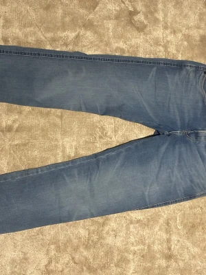 Blå jeans från Replay - Säljer ett par klassiska blå jeans från Replay med fem fickor och en clean look. Jeansen har normal midja och tajta en fin passform runt bena, tillverkade i mjukt denimtyg som ger en skön känsla. Perfekta för dig som gillar en avslappnad men stilren look. Skick 10/10 aldrig använda priset kan diskuteras hör av er vid minsta lilla !