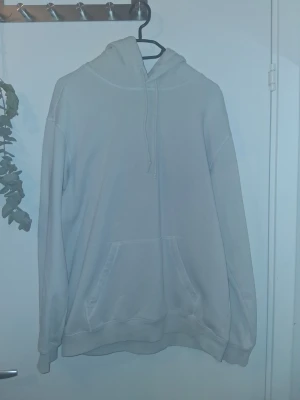 Ljus beige basic hoodie med ficka - En stilren ljus beige hoodie med huva och dragsko. Hoodien har en stor magficka framtill och ribbade muddar vid ärmslut och nederkant. Perfekt för en avslappnad och enkel look. Materialet känns mjukt och bekvämt mot huden.