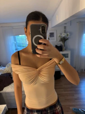 Ljusbeige omlott topp från Amisu - Säljer en ljusbeige omlott topp från Amisu med offshoulder-design och snygg twistad detalj framtill. Toppen är figurnära och har en mjuk, stretchig känsla som passar perfekt till jeans eller kjol.