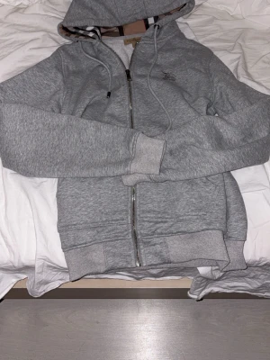 Grå hoodie från Burberry med dragkedja - Snygg grå hoodie från Burberry med dragkedja. Den är nyskick och storlek S