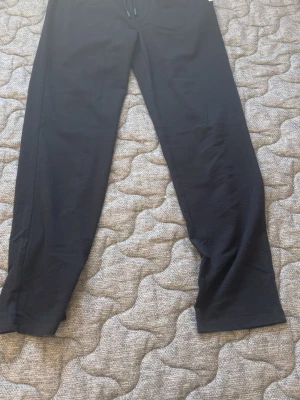 Svarta mjukisbyxor med raka ben - Svarta mjukisbyxor med raka ben och dragsko i midjan. Byxorna har en enkel och stilren design, perfekta för en avslappnad look. Mjukt och bekvämt material som passar för chill eller träning.