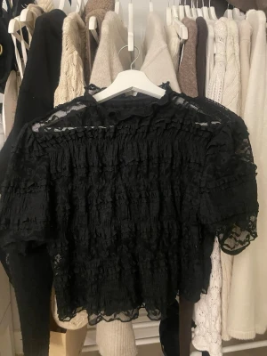Svart spetsblus med volangdetaljer - Säljer en svart blus i spets med volangdetaljer.