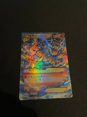 Pokémonkort Mega Charizard EX - Jag har ett Mega Charizard-kort som jag fick i present av en kompis. Jag är dock osäker på om det är äkta eller inte, och det är inte i särskilt bra skick. Men kul för de som vill utöka sin samling.