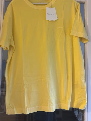 Gul t-shirt från GANT helt ny med tag . (Nypris 650 ) - Fräsch gul t-shirt från GANT med klassisk rund hals och diskret broderad logga på bröstet. 
