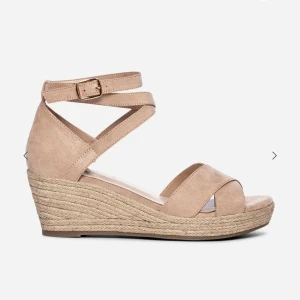 Beige kilklackssandaler LINEAR - Snygga gammelrosa/beige sandaler från LINEAR med kilklack och korsade remmar i mockaimitation. Justerbar ankelrem med spänne och flätad sula i espadrillestil ger en trendig look. Perfekta för sommarens outfits och lätta att matcha med olika stilar.