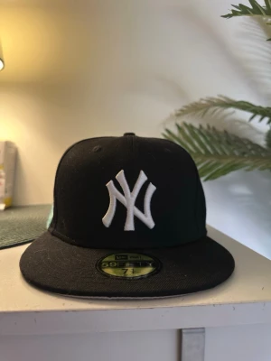 Svart New Era Yankees keps - Snygg svart keps från New Era med New York Yankees-logga broderad framtill i vitt. perfekt för streetwear och sportiga outfits.