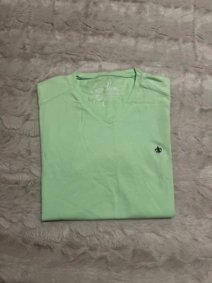 Ljusgrön t-shirt från Lucio Uomo - Fräsch ljusgrön t-shirt från Lucio Uomo med v-ringning och liten broderad detalj på bröstet. Tillverkad i mjuk bomull och har korta ärmar. Perfekt för en avslappnad och stilren look.