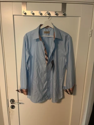 Ljusblå skjorta från Burberry - Säljer nu min sjukt snygga burberry skjorta som aldrig kommit till använding. Storlek L men sitter mer som M! 