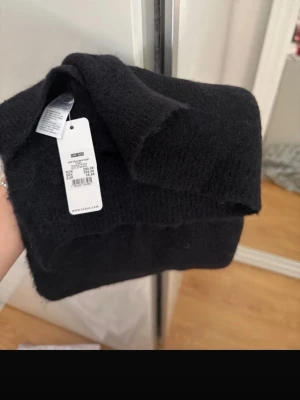 Svart halsduk från Cubus i ullmix - Mysig svart halsduk från Cubus i en mjuk ullblandning. Enkel och stilren design som passar perfekt till kalla dagar. Halsduken är enfärgad och har en klassisk rektangulär form. Perfekt accessoar för att hålla värmen och lyfta din outfit.