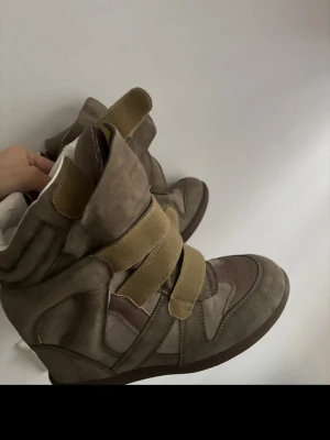 Oliv gröna  Isabel Marant sneakers med kardborre - Säljer ett par oliv gröna  sneakers från Isabel Marant med högt skaft och breda kardborreband. Skorna har en cool, chunky design i mocka och lädermix med vita detaljer på insidan. Perfekta för dig som gillar statement-sneakers med unik look.