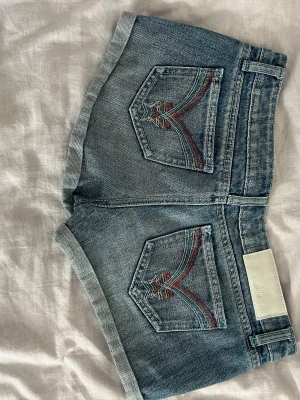 Shorts somriga - Snygga shorts med vissa sömmar i turkos färg och även knapparna är turkosa. Fickorna bak har motiv med flera olika färger broderat eller sytt de är från Gina jeans. 90% bomull 10% polyester vilket gör shortsen mycket slitstarka Pm vid yttligare frågor❤️🫶    