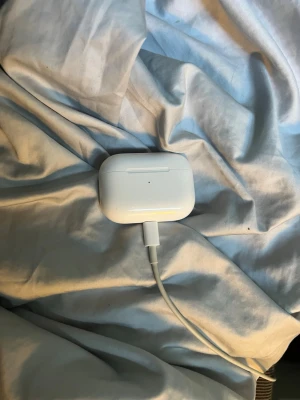 Apple AirPods Pro  - Säljer ett par vita Apple AirPods Pro med trådlöst laddningsetui. Hörlurarna har en stilren och kompakt design med silikonproppar och touchkontroller. Perfekta för musik, samtal och träning. Laddas enkelt via lightning-kabel. Boxen finns inte då den är slängd, Lightning kabel ingår 