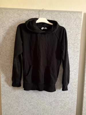Svart basic hoodie - En stilren svart hoodie med huva och stor magficka. Klassisk modell. Materialet känns mjukt och bekvämt, passar till det mesta i garderoben.