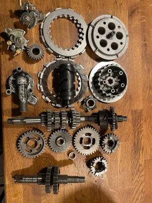 Motorcykeldelar i metall - Ett blandat kit med motorcykeldelar i metall, inklusive kugghjul, axlar, kopplingsdelar och andra mekaniska komponenter. Delarna är av stål och har en industriell, robust design. Perfekt för dig som gillar att meka eller behöver reservdelar till motorcykel.
