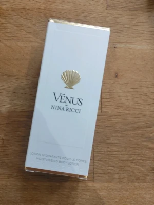 Vénus body lotion från Nina Ricci - Lyxig återfuktande body lotion från Nina Ricci i serien Vénus. Kommer i en elegant vit förpackning med gulddetaljer och snäckmotiv. Perfekt för dig som vill ha en mjuk och väldoftande hud.