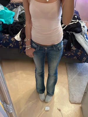 Ljusrosa ribbad linnetopp - Säljer en ljusrosa, tight och ribbad linnetopp med smala axelband. Toppen är figurnära och har en enkel, stilren design utan mönster eller detaljer. Perfekt att matcha med jeans eller kjol för en clean look.