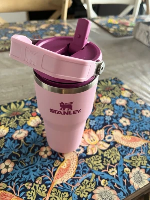 Stanley Iceflow Flip Straw 2.0 Tumbler 0,6l - Stanley Iceflow Flip Straw 2.0 Tumbler 0,6l med lila detaljer och metallkant upptill. Muggen har ett praktiskt lock med drickpip och handtag, perfekt för att ta med dryck på språng. Tillverkad i rostfritt stål och plast.