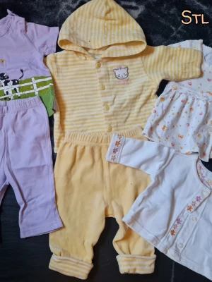 Sött babyklädpaket i pastellfärger - Ett gulligt paket med babykläder i pastellfärger. Innehåller en gul- och vitrandig hoodie med kattmärke, matchande byxor, lila set med kattmotiv, vit klänning med små figurer och vit kofta med blommiga detaljer. Perfekt för mysiga dagar.
