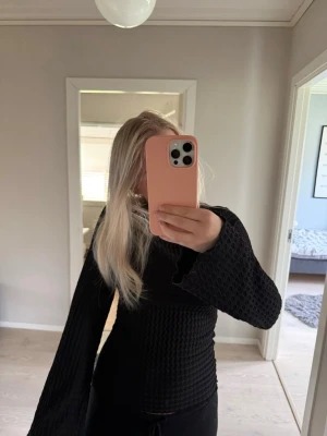 Svart tröja med vida ärmar - Säljer en svart, figurnära tröja med snyggt strukturerat mönster och vida trumpetärmar. Tröjan har rund halsringning🌸säljer den eftersom den bara hänger i garderoben och kommer aldrig till användning🌸Köparen står för frakt. 