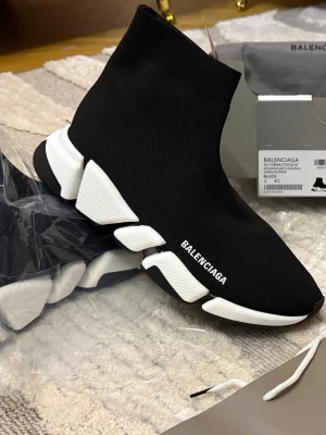 Balenciaga svart Speed 2.0 sneaker - Svarta Balenciaga Speed 2.0 sneakers med vit chunky sula och stickad ovandel i textil. Strumpliknande passform och tydlig logga på sidan. Snygg och futuristisk design som sticker ut i mängden.