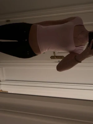 Ljusrosa croppad topp med kort ärm - Säljer en ljusrosa croppad topp med korta ärmar och fyrkantig ringning. Toppen har en tight passform och är perfekt för en trendig look. Materialet känns mjukt och stretchigt, vilket gör den bekväm att bära hela dagen.