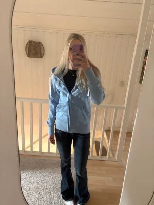 Russemerch Ljusblå hoodie med dragkedja - Säljer en ljusblå hoodie med dragkedja från märket Russemerch. Hoodien har huva, fickor framtill och är gjord i ett mjukt material som känns skönt mot huden. Perfekt för en avslappnad och chill stil.