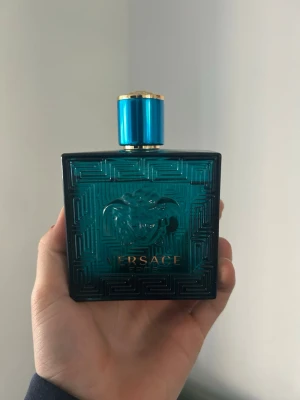 Versace Eros Eau de Toilette - Versace Eros parfym i en stilren, fyrkantig flaska av blågrönt glas med guldiga detaljer och Medusa-loggan. Flaskan har ett lyxigt och modernt utseende, perfekt för dig som gillar exklusiva dofter och snygg design.    Nästan allt finns kvar bara använt några gånger 