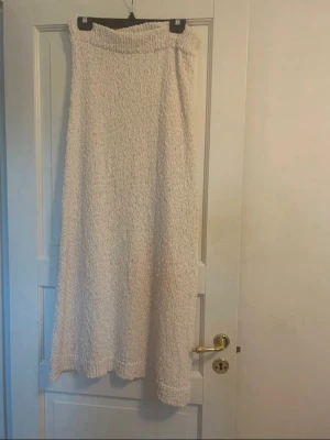 Beige stickad långkjol - Mysig beige stickad långkjol med grovstickat mönster. Kjolen har en rak och avslappnad passform och är perfekt för dig som gillar en enkel men trendig stil. 