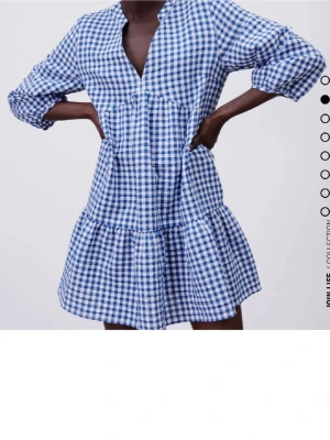 Blåvit rutig kort klänning - Supersöt kort klänning i blåvitt rutigt mönster med v-ringning och trekvartsärm. Klänningen har en lös passform och volang nedtill, perfekt för en avslappnad och trendig look.