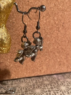 Silvriga ängelörhängen i metall - Handgjorda unika örhängen i silverfärgad metall med detaljerade ängelmotiv. Hängande modell med krok, perfekta för dig som gillar statement-smycken med vintagekänsla. Passar till alla tillfällen när du vill sticka ut lite extra. Ej nickelfria.