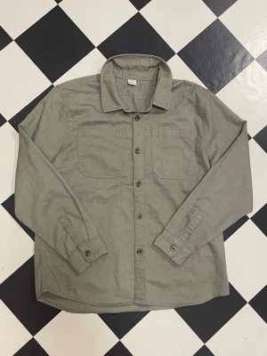 Snygg Olivgrön Skjorta🍾💚st: 170 - 💚 Olivgrön långärmad skjorta – stl 170 💚  Snygg och stilren olivgrön skjorta i storlek 170 🌿 Perfekt både till vardag, skola eller lite mer uppklätt tillfälle 👌✨ Färgen är supertrendigt och lätt att matcha med jeans, cargo eller svarta byxor 🤎🖤  🧵 Skicket är mycket bra – redo för en ny ägare! 💰 Pris: endast 79 kr (riktigt kap!)  📏 Mått: • Armlängd: 58 cm • Längd: 66 cm • Axelbredd: 45 cm  Perfekt passform för dig som brukar ha 170 / XS 👕💫