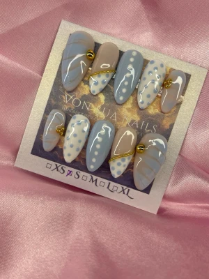 BlueBijou (S);Medium Almond - Snygga handgjorsa press-on naglar i en medium mandelform. Mix av ljusblått och nude med blåa prickar och guldfärgade kedjedetaljer. Perfekt för dig som vill ha en unik och trendig nagelstil. S: 15 mm, 11,5 mm, 12 mm, 11 mm, 9 mm 