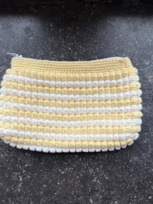 Necessär - Söt handgjord necessär i gult och vitt med virkade ränder och bubblig struktur. Perfekt för småsaker eller smink.