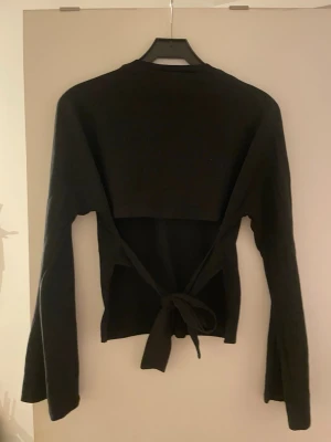 Svart långärmad Nelly top med knyt där bak - En svartlångarmad jättefin tröja från Nelly med en öppen rygg som man kan knyta!☺️I strl Xs, hör av dig till mig om du vill köpa! 