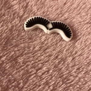 Ögonfransar i plast - Säljer ett par ögonfransar som är svarta med vita konturer, tillverkade i plast. Funkar som en pin som man kan ha på mobilskalet eller på nåt annat random, OBS! Finns inte klister på baksidan så man får klistra på själv.