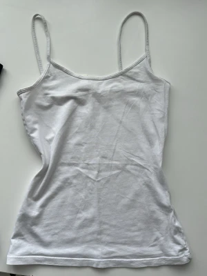 Svart och vit linnetopp med smala band - Två stilrena linnetoppar i svart och vitt med smala axelband och enkel, figurnära passform. Perfekta att matcha till olika outfits och tillverkade i mjuk bomull för skön känsla hela dagen.