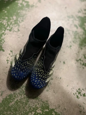Adidas blå-svarta fotbollsskor - Säljer ett par Adidas fotbollsskor i blått och svart med gula detaljer. Skorna har en strumpliknande passform utan snörning och mönstrad ovandel för extra grepp på bollen. Perfekta för dig som vill ha kontroll och stil på planen. Nypris 600