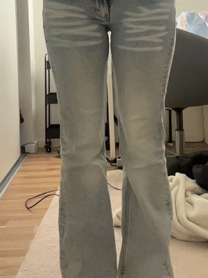 Ljusblå bootcut jeans med slitningar - Säljer ett par ljusblå bootcut jeans med slitningar framtill och lätt tvättade detaljer. ytters lite nertrampade vid ena byxkanten. storlek 27/30 och passar mig som är 163