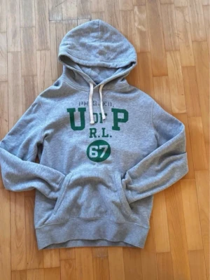 Ralph Lauren hoodie  - Säljer skit fet Ralph Lauren hoodie, storlek xs, 10/10 skick, perfekt hoodien nu när det är kyligt och inför våren, grå hoodie med gröna detaljer, kommer inte gå ned för mycket i pris då det är en rätt unik hoodie 