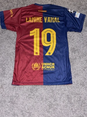 Barcelona matchtröja Lamine Yamal #19 - Fake Barcelona hemma matchtröja 24/25. Med Lamine Yamal nummer 19 och Champions League logga på ärmen.