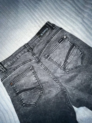 Grå bootcut jeans från Garcia - Grå jeans från Garcia med bootcut-modell och tvättad finish. Jeansen har klassiska fem fickor, bälteshällor och tydliga sömmar. Materialet är denim med en mjuk känsla och cool vintage-look. Perfekta för dig som gillar en avslappnad och trendig vibe.