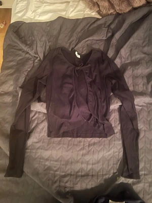 Svart omlottopp med knyt från Kappahl  - Trendig svart omlottopp med knyt framtill och långa ärmar. Toppen är ribbad och har en smickrande v-ringning. Perfekt att styla med jeans eller kjol för en cool look. Använd några gånger och är i storlek 158/164💓💓