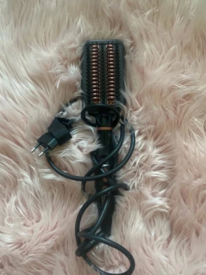 Svart värmeborste från California Beauty - Elektrisk värmeborste i svart med kopparfärgade detaljer och digital display. Handtaget har knappar för temperaturkontroll och borsten har keramiska värmeelement. Perfekt för att styla håret snabbt och enkelt.