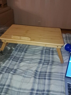 Hopfällbart bambubord för säng - Säljer ett hopfällbart bord i ljust bambuträ, perfekt att använda i sängen eller soffan. Bordet har fyra ben och en liten kant för att hålla laptop eller böcker på plats. Smidig och lätt design som gör det enkelt att flytta runt.