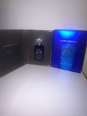 Clive Christian Addictive Arts parfym - Lyxig parfym från Clive Christian, Addictive Arts-serien. Flaskan är djupblå med gulddetaljer och har en elegant, genomskinlig kork. Kommer i exklusiv blå och svart förpackning med metallic-effekt. Perfekt för dig som gillar exklusiva dofter och snygg design.
