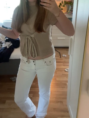Vita raka jeans med låg midja - Säljer ett par vita jeans med bootcut passform och låg midja. Jeansen har klassiska fem fickor, bälteshällor och stängs med knapp och dragkedja. Perfekta för en clean och fräsch look.